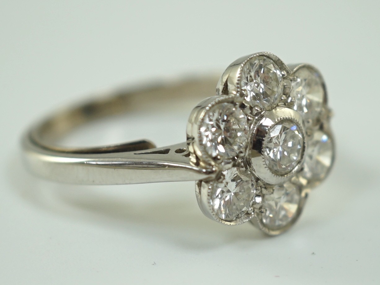 A platinum and seven stone diamond cluster set flower head ring